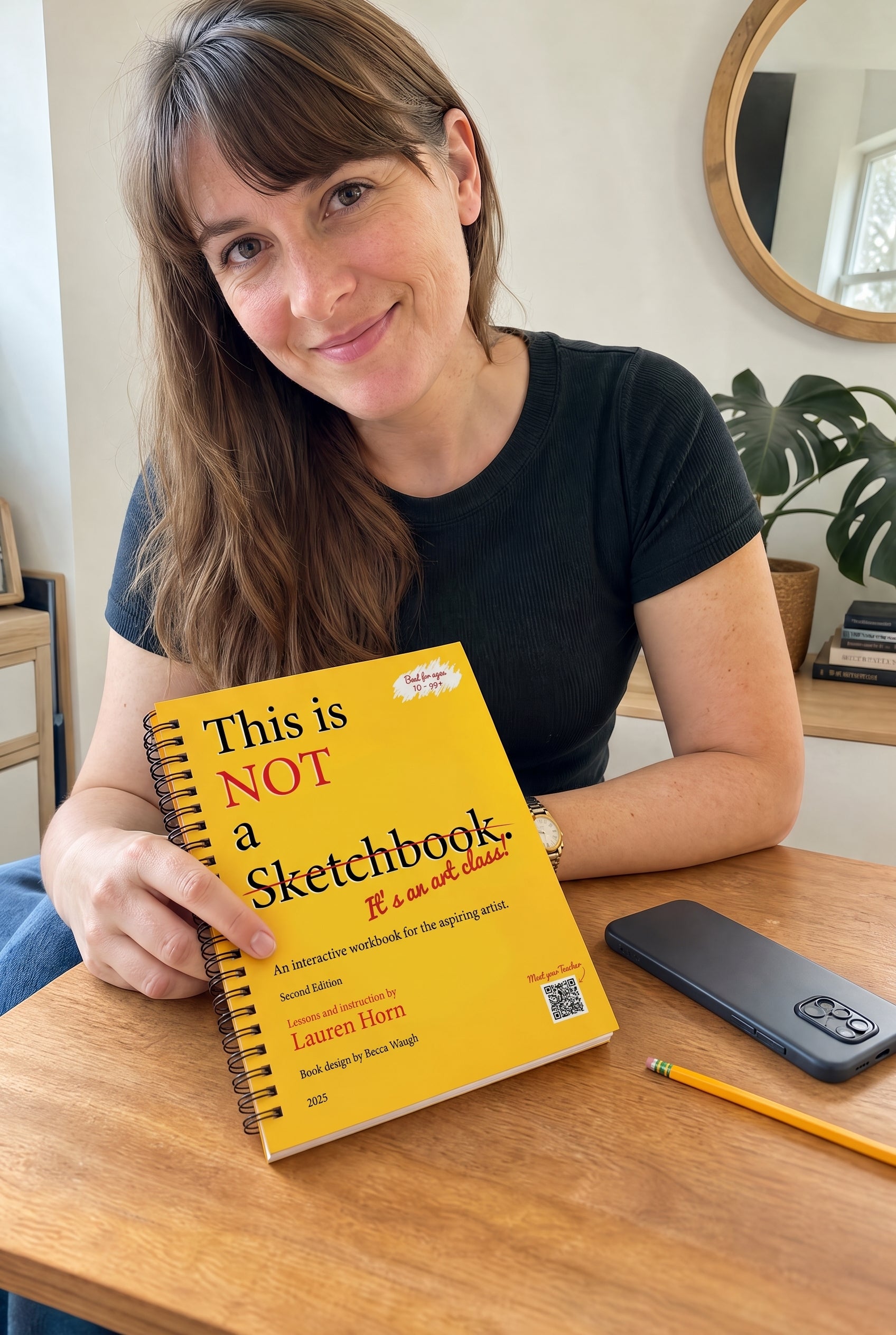 The hardcover 'This is Not a Sketchbook' art class book beside a face-down phone on a clean desk